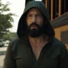 A hooded Frank Castle standing in front of a US school bus in The Punisher: One Last Kill