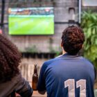 Group of people watching a sports event on TV.