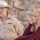 Beth smokes while leaning against a wooden fence with Zachariah standing behind
