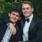 Nick and Charlie wear tuxedos and pose for a photo