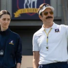 Jason Sudeikis as Ted Lasso in a white visor and sunglasses pointing across the pitch next to Tanya Reynolds as Alice Chilton in AFC Richmond training gear