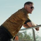 Tom Hardy leans on a metal railing