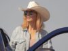 Beth Dutton looks on while standing behind an open car door